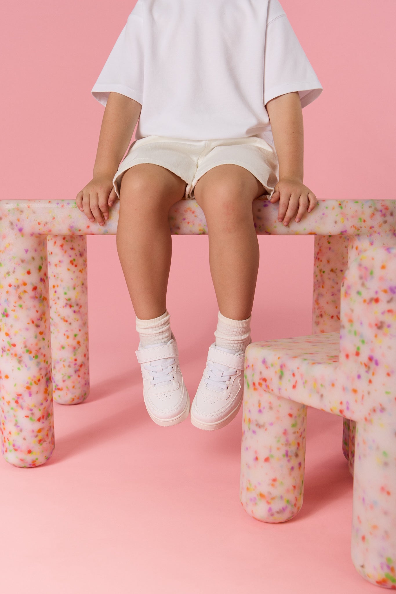 Person sitting on a colorful chair with a pink background