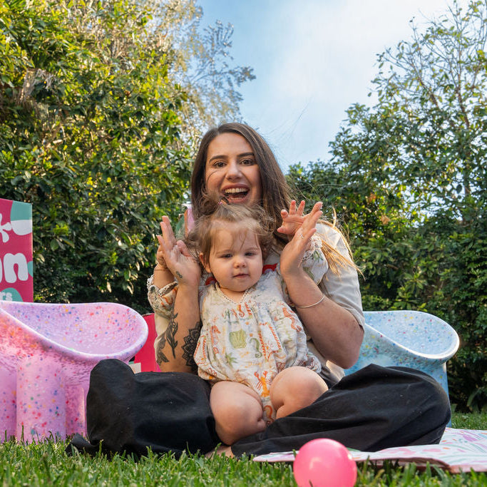 Woman and child sitting on grass with Jelly Bean Interiors packaging in the background